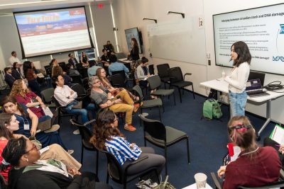 A graduate student presents her research findings at the Cancer Research Symposium.